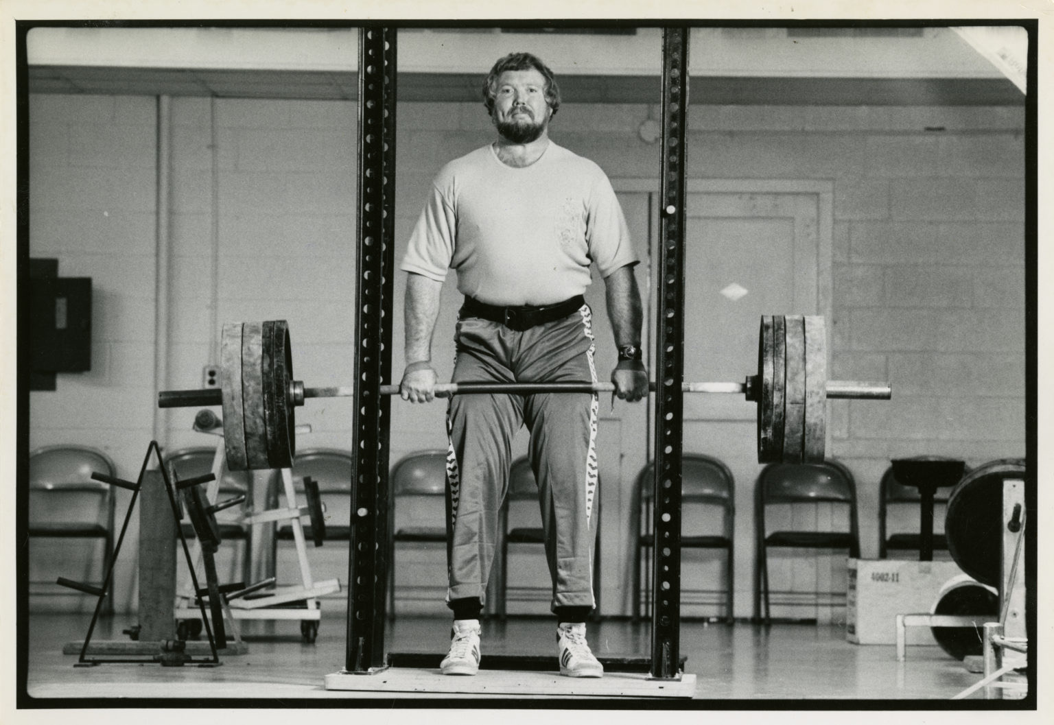 Black and white photo of weightlifter Terry Todd standing and holding a barbell with weights.