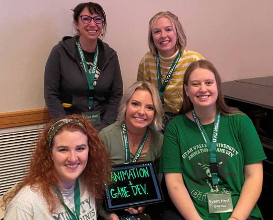 Five female Animation and Game Development students pose for the camera where the one in the middle is holding a sign reading Animation and Game Dev.