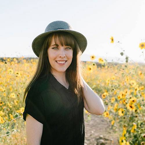 Picture of Lauren Madsen with a sunhat on in a field of flowers