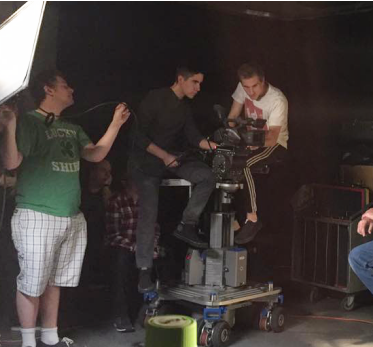 Two students riding dolly and one using a reflector