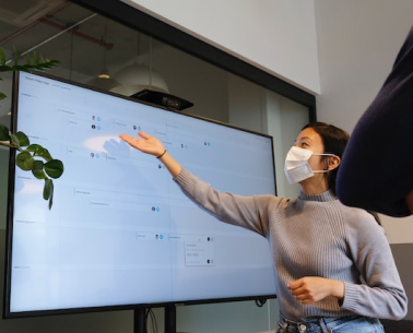 Women in a mask pointing at a Television