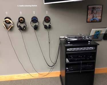 Audio turntable, CD Player, and receiver, with headphones hanging on the wall.