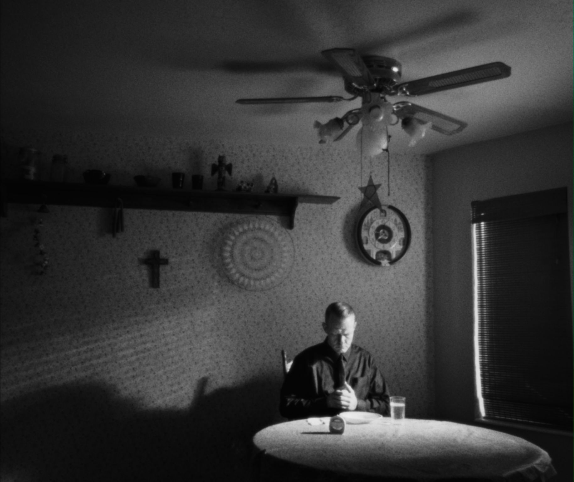 a wide shot of a man sitting at a table in a mostly empty room