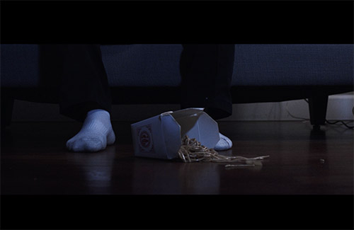 a chinese takeout container with noodles spilled on the floor