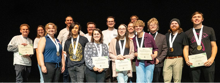 students standing on a stage with medals and certificates