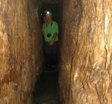 Man in a cave with a headlight documenting Beit Lehi