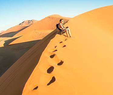 Student sitting on a sand dune