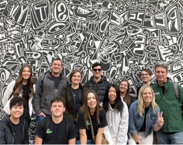 A group of students standing behind a black and white mural