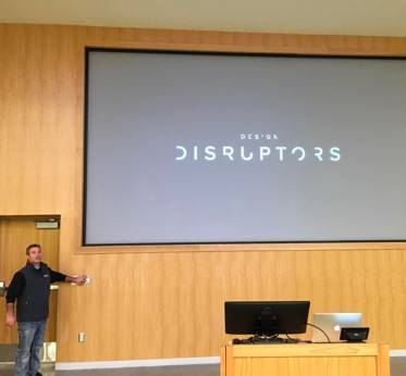 Michael Harper dimming the lights for the movie premiere on the screen behind him