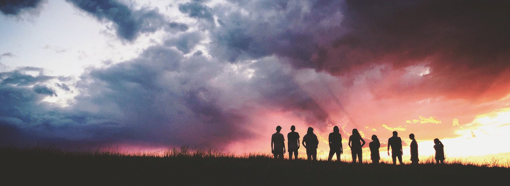 A team standing on a hill at sunrise.