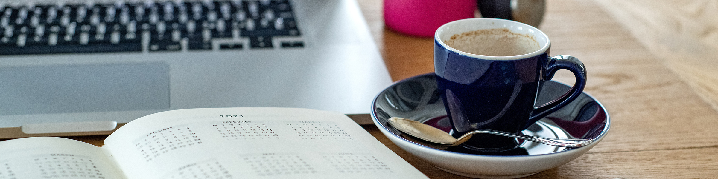 An employee desk with a blue cup of coffee. 