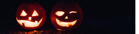 Two jack-o-lanterns glowing in the dark.