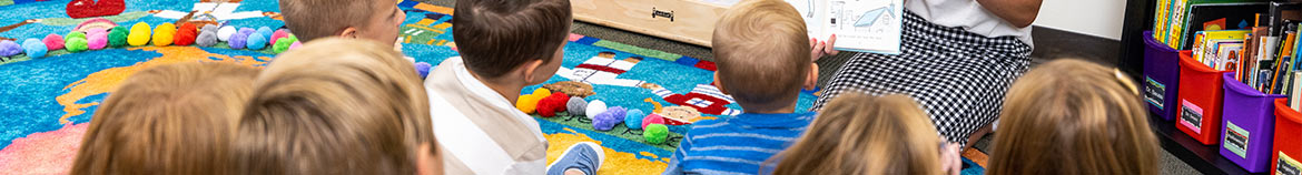 young children in a classroom sitting on a colorful rug