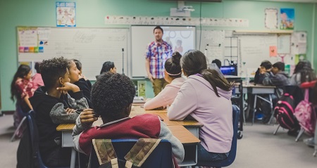 Students in a classroom listening to their teacher.