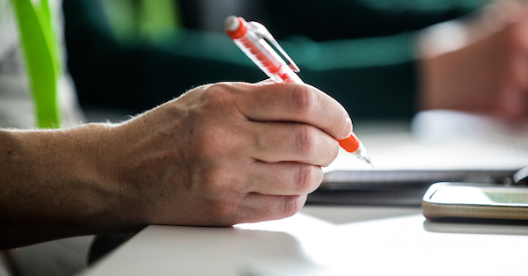 pen in hand hovering over desk