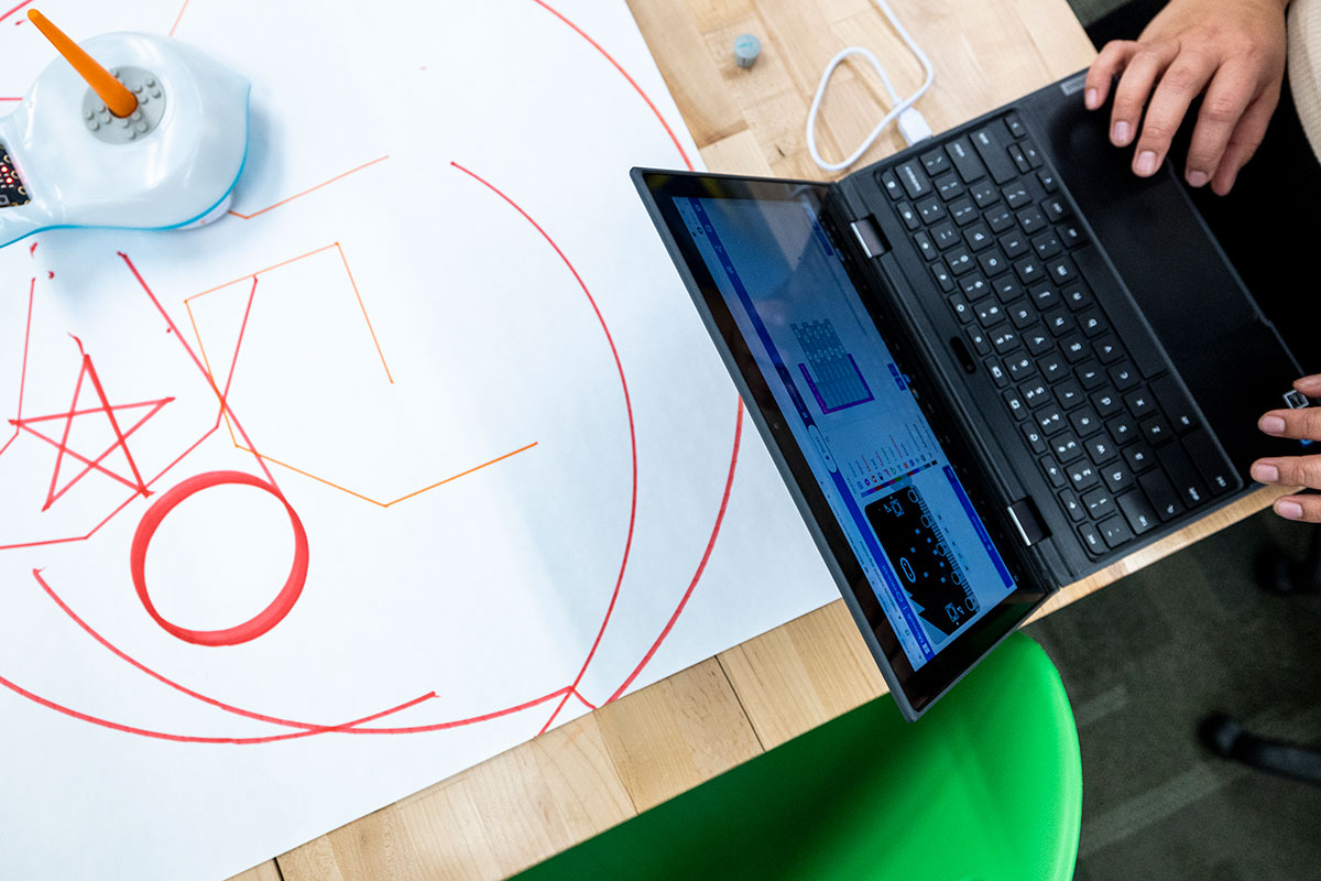 image of a person on a laptop at a desk decorated with drawn on paper