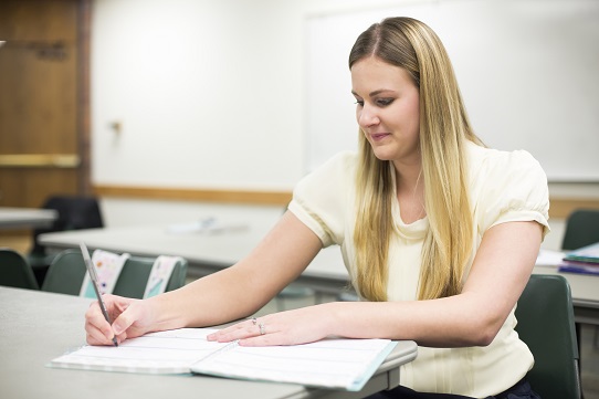 college student writing in book