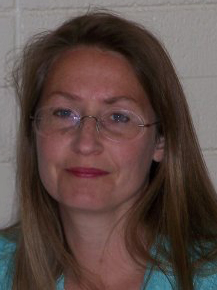  A headshot of Susan Guinn with light brown hair and glasses