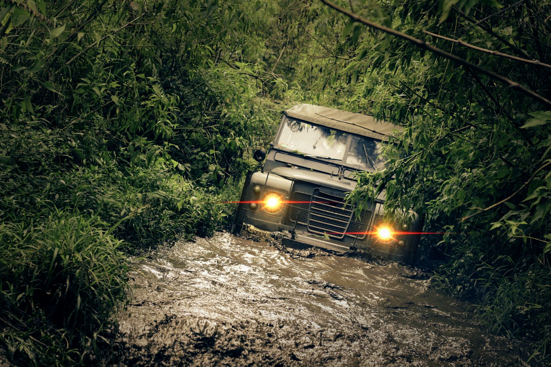 Green car on flooded muddy road in forest - Image by Ahmad Syahrir from Pexel 