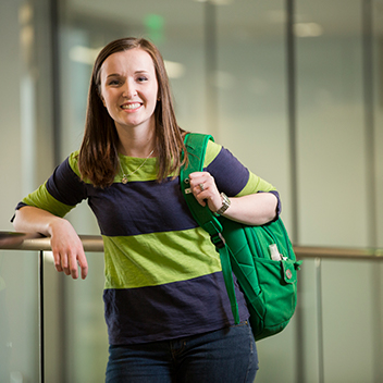 Dark hairded Female Student with backpack leaning on railing