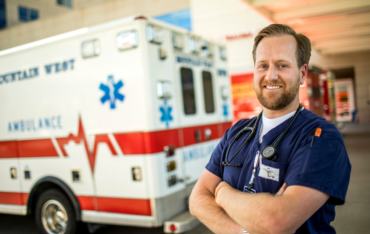 an ambulance worker posing in front of an ambulance