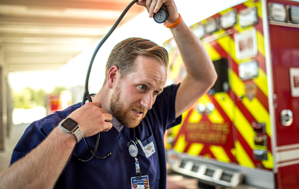 Professional taking off stethoscope in front of ambulance - action shot