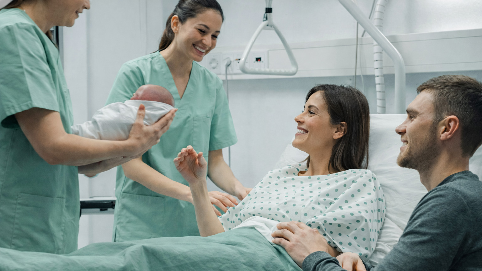 Nurse handing a baby to the mom and dad