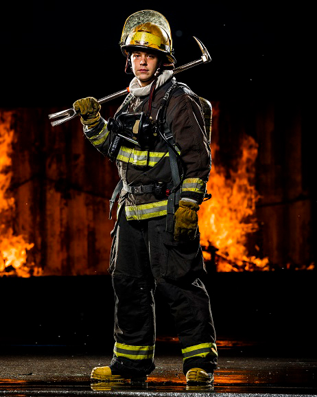 Fireman standing in front of a fire with a crowbar