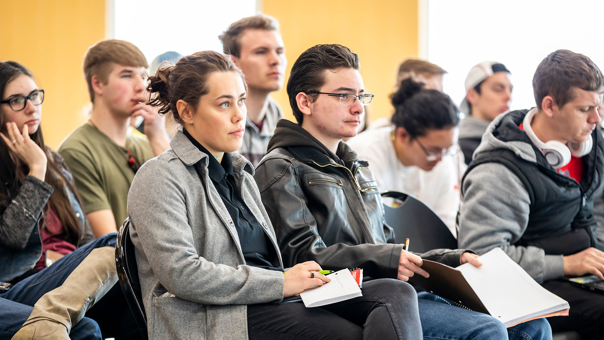 Woman sits listening to a lecture. 