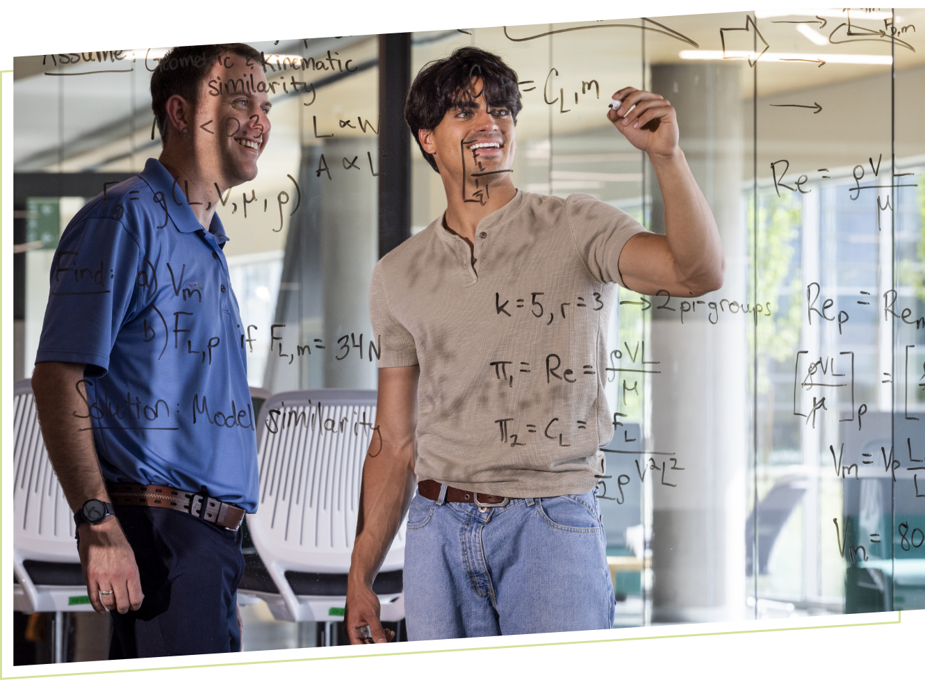 two students working on glass dry erase board