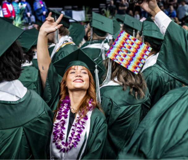 female graduate in cap and gown in a crowd of other students