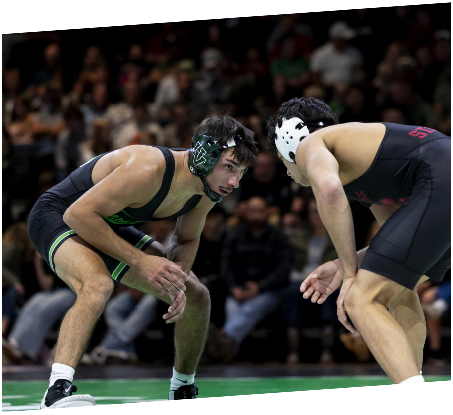 two UVU wrestlers crouch and face each other in preparation for a match