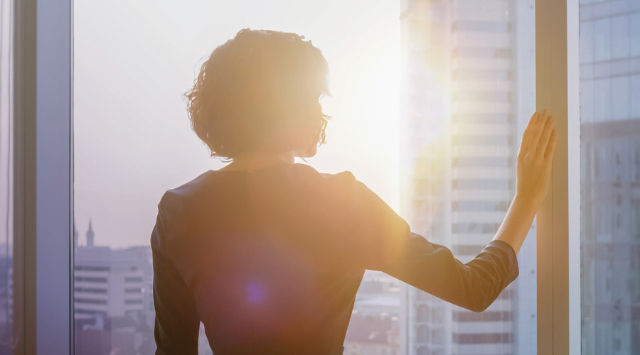 Woman standing at window in sunlight