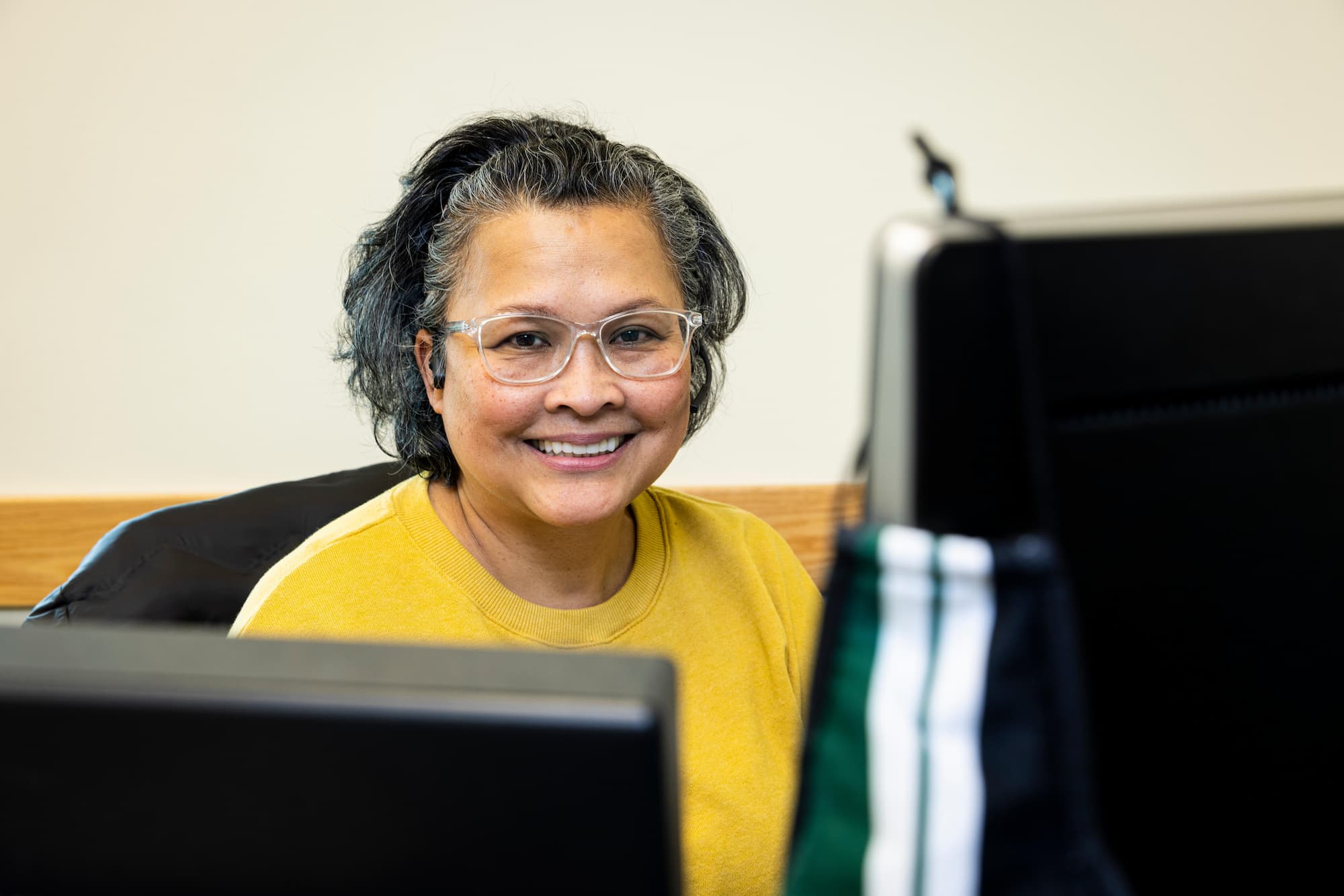 A photo of an admin smiling while sittting at a desk