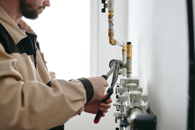 repairman with wrench fixing pipe