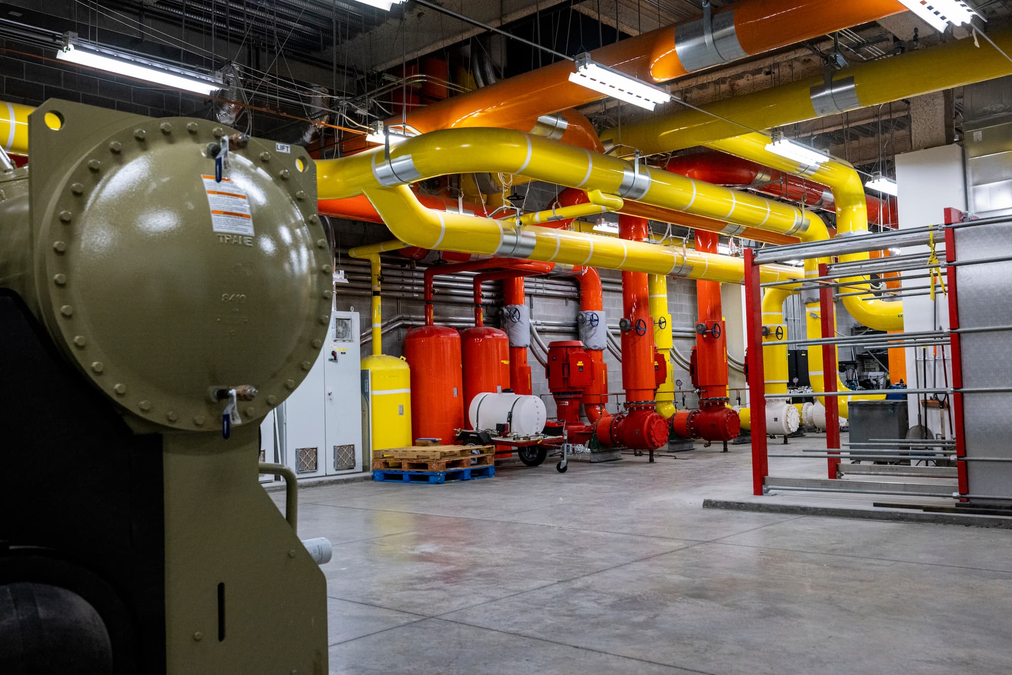 An HVAC tech room, with multicolored pipes and various equipment.