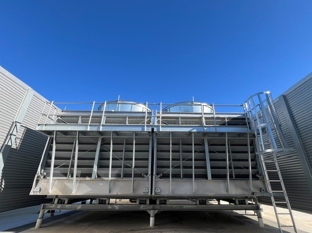 Large cooling tower on top of a rooftop blue sky above