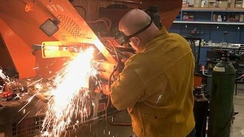 Person working to weld metal in workshop.