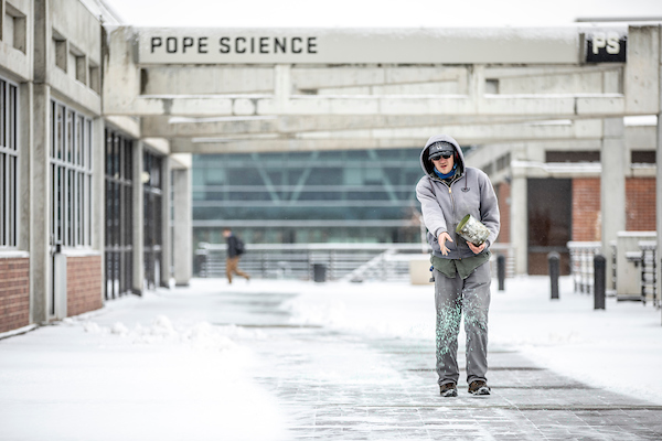 Person pouring salt on walkways