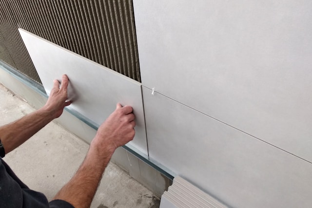 person placing wall tiles