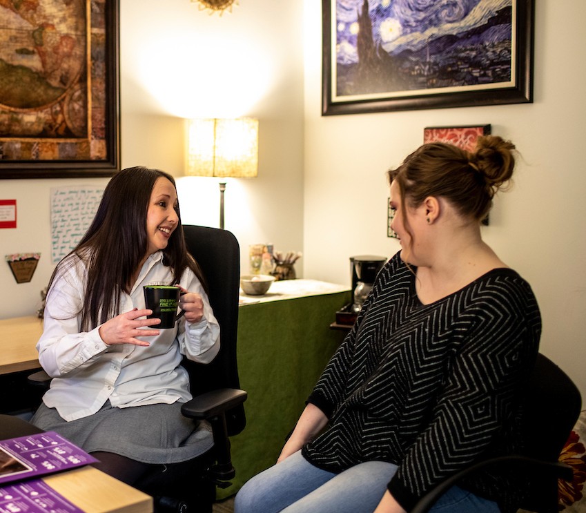 Two adults sitting in an office having a conversation