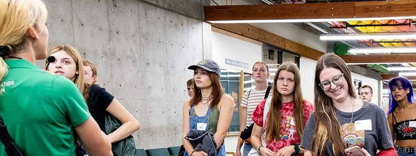 A UVU employee walking backwards giving a tour to students during orientation.