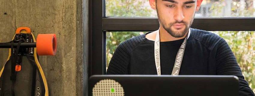 A student sitting in a chair looking at his laptop.