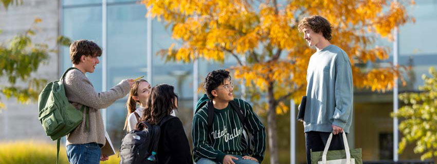 A group of students, dressed in UVU merch, huddled together taking a picture.