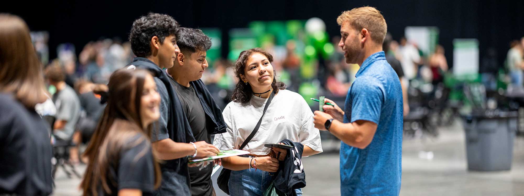 A group of new students listen to a man giving information about UVU.