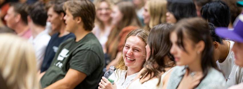 Students sitting in rows listening to UVU orientation.