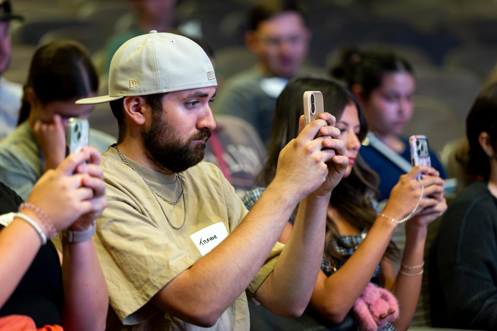 Students sitting a table, have their phones out taking a picture of something in front of them.