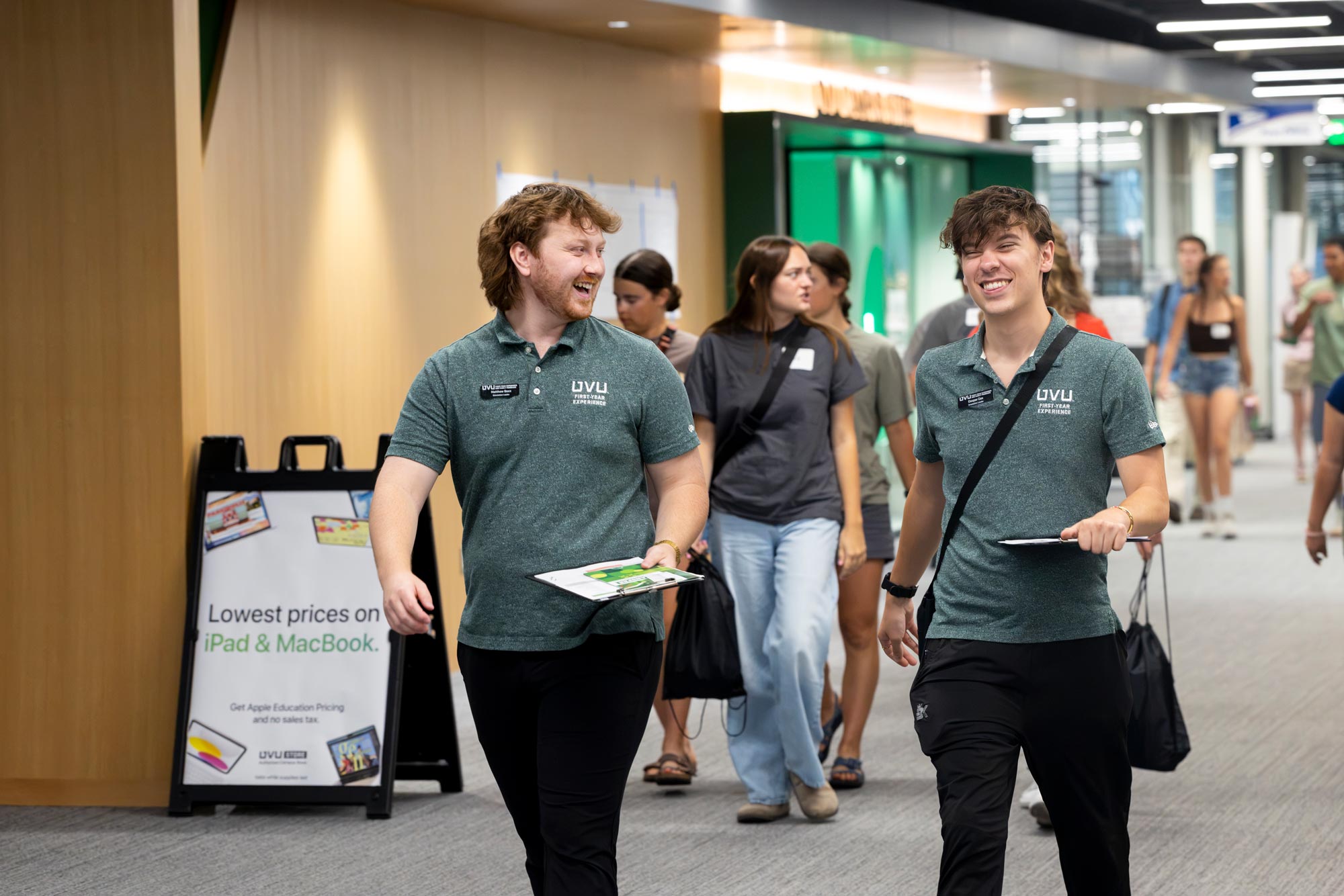 Two tour guides walk together down one of UVU's hallways.