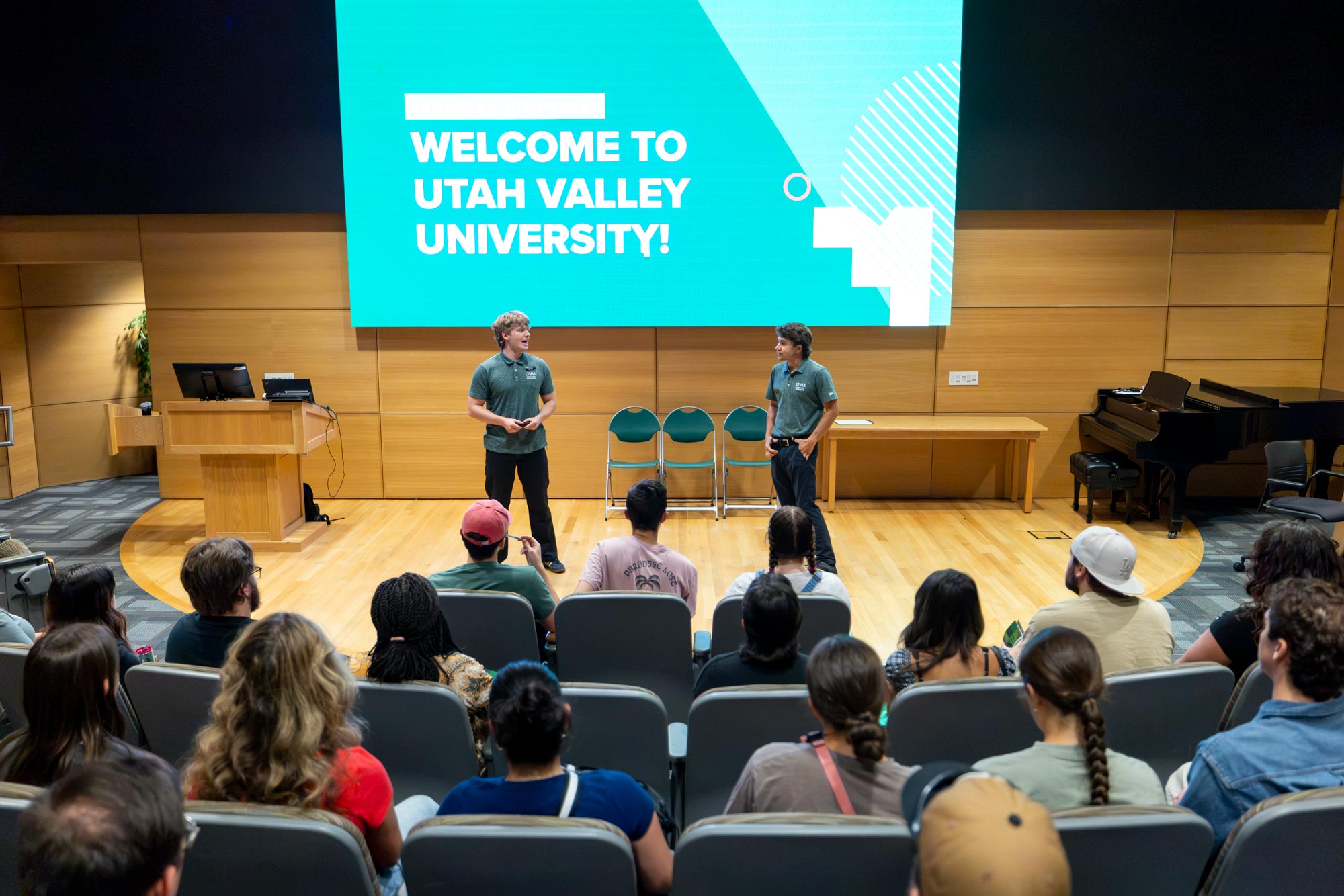 People on stage giving a presentation to a crowd of students.