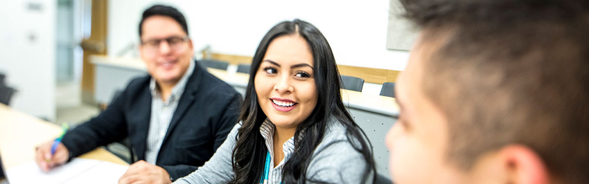 A woman sitting inbetween two men, and she is looking at the man on the right.
